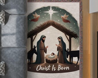 Puede incluir: Una manta tejida con una escena de la Natividad con el texto "Christ Is Born". La ilustración representa a María, José, el niño Jesús, ángeles y burros bajo un cielo estrellado. La manta tiene un borde con flecos.