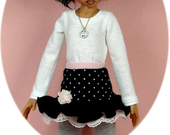 May include: A doll with dark hair wearing a white long-sleeved shirt, a black and white polka dot skirt with a pink ruffle, and a silver peace sign necklace.