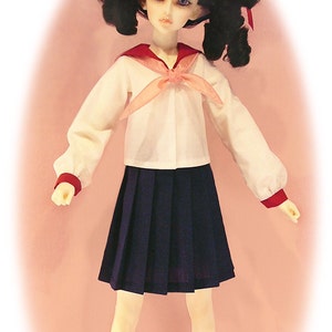 May include: A doll wearing a white sailor uniform with a pink bow tie, a dark blue pleated skirt, and red shoes. The doll has black hair with red bows and blue eyes.