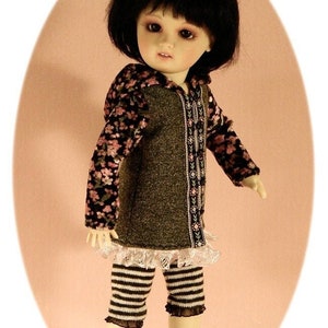 May include: A doll wearing a brown and black hooded sweater with floral print sleeves, a white lace trim, and black and white striped leggings.