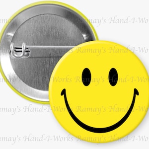 May include: A yellow button with a black smiley face. The button has a metal back and a pin for attaching to clothing.