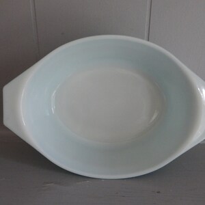 May include: Oval-shaped, light blue and white casserole dish with handles. The dish has a smooth, glossy finish and a slightly flared rim. A classic piece for baking and serving.