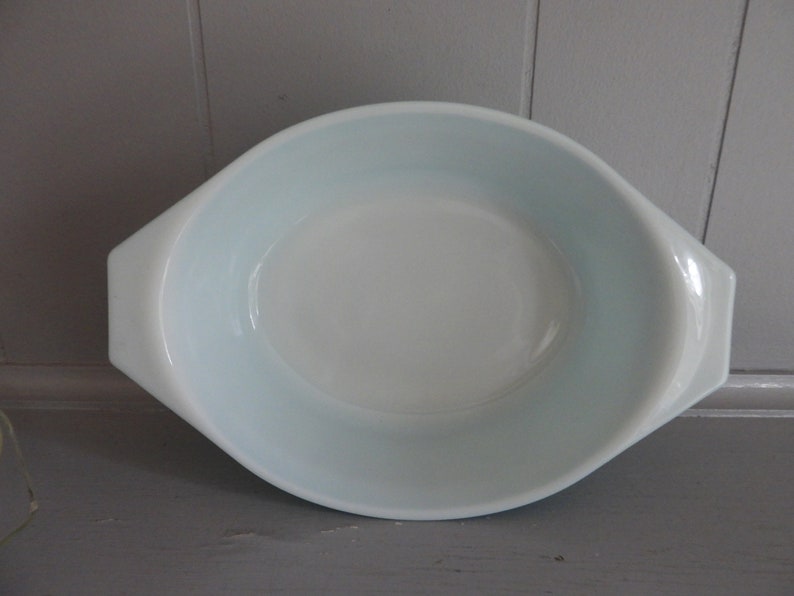 May include: Oval-shaped, light blue and white casserole dish with handles. The dish has a smooth, glossy finish and a slightly flared rim. A classic piece for baking and serving.