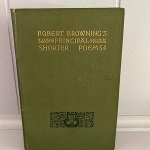 May include: A hardcover book with a solid olive green cover. The front cover features gold embossed text that reads ROBERT BROWNING'S PRINCIPAL SHORTER POEMS, accompanied by small decorative floral motifs and a dark green lyre icon at the bottom.