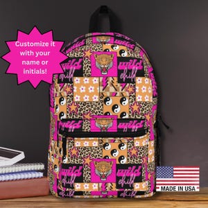Könnte beinhalten: Ein Patchwork-Rucksack mit einem lebendigen Design mit Tigergesichtern, Sternen, Yin-Yang-Symbolen und den Worten "wild child". Der Rucksack hat einen schwarzen Griff und Reißverschluss und wird in den USA hergestellt.