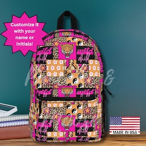 Puede incluir: Una colorida mochila con un diseño de patchwork que presenta estampado de leopardo, flores, estrellas y el texto "wild child". La mochila tiene un asa y cremallera negras, con una combinación de colores rosa y naranja. También es visible el texto "Customize it with your name or initials!"