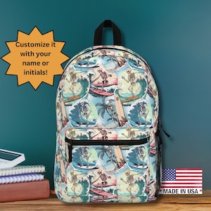 May include: A backpack with a repeating pattern of skeleton surfers riding waves. The design includes palm trees, surfboards, and a blue and teal color scheme. The backpack has a black handle and a front zippered pocket. The text "Customize it with your name or initials!" is in a starburst.