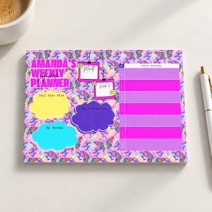 May include: A rectangular weekly planner notepad with a colorful butterfly pattern background. It features the text AMANDA'S WEEKLY PLANNER, sections for Month and Week of, a Self Care Area, Top Priorities, My Notes, and a Weekly Breakdown table.