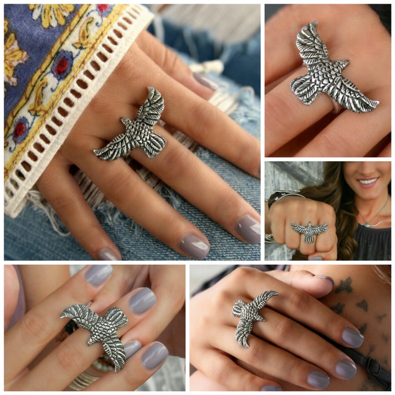 May include: A silver ring featuring a detailed design of a bird in flight. The ring is shown on a person's finger.