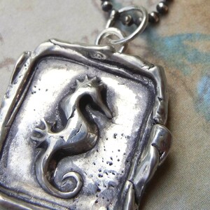 May include: Silver pendant necklace featuring a detailed, three-dimensional seahorse design. The pendant is square-shaped with a textured, aged finish.