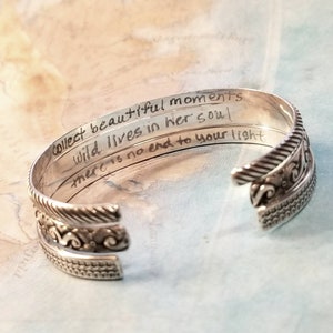 May include: Silver bangle bracelet with an engraved inscription that reads "Collect beautiful moments wild lives in her soul there is no end to your light".