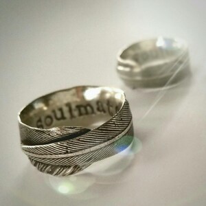 May include: A silver ring with a feather design and the word "soulmate" engraved on the band.