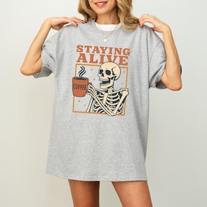 Staying Alive Skeleton Coffee Shirt: Funny Dark Humor Graphic Tee