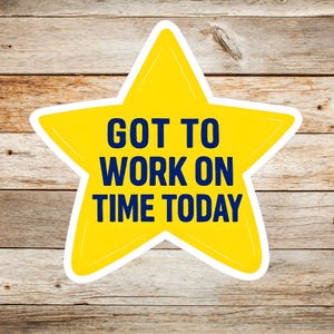 May include: A yellow star-shaped sticker with the text "GOT TO WORK ON TIME TODAY" in navy blue. The sticker has a white border and is set against a wooden background.