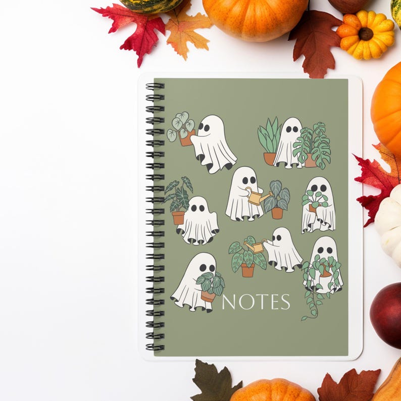 May include: A spiral-bound notebook with a sage green cover featuring a repeating pattern of white ghosts interacting with various potted houseplants. One ghost holds a watering can, while others hold or stand near plants. The word NOTES is printed in white.