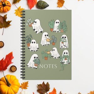 May include: A spiral-bound notebook with a sage green cover featuring a pattern of white ghosts interacting with various potted houseplants. The word NOTES is printed in white at the bottom centre. The ghosts are shown holding or watering plants.