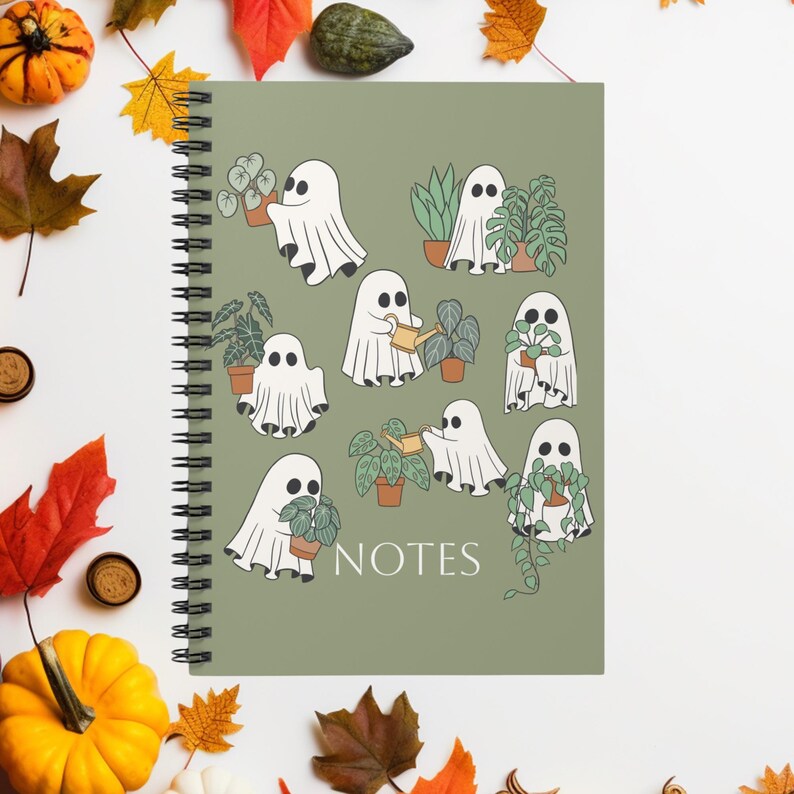 May include: A spiral-bound notebook with a sage green cover featuring a pattern of white ghosts interacting with various potted houseplants. The word NOTES is printed in white at the bottom centre. The ghosts are shown holding or watering plants.