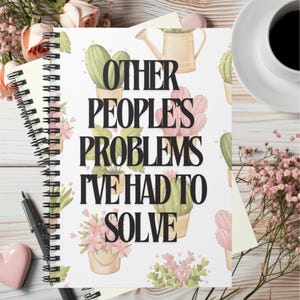May include: A white spiral bound notebook with a cactus and floral pattern. The text "Other People's Problems I've Had To Solve" is printed in black on the front cover.