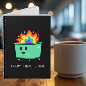 May include: A black spiral notebook with a green trash can with flames on top and the text "EVERYTHING IS FINE".
