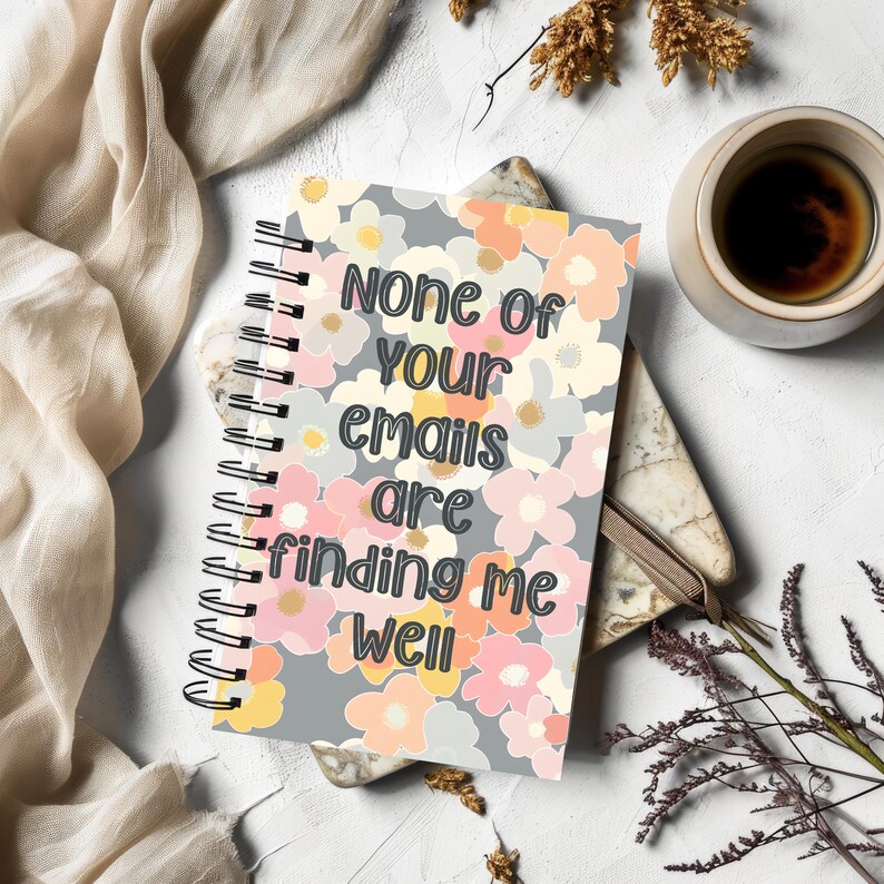 Może przedstawiać: Szary notes spiralny z kwiatowym wzorem i tekstem "None of your emails are finding me well".