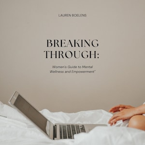 May include: A laptop computer is open on a white bedspread. The laptop screen is black. The text "BREAKING THROUGH: Women's Guide to Mental Wellness and Empowerment" is displayed on a beige wall behind the laptop.