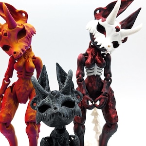 May include: Three articulated skeleton figures with horns and a skull-like face. The figures are painted in red, orange, and black.