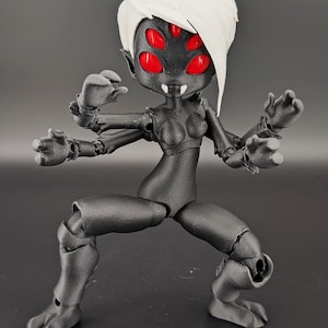 May include: A black articulated figurine of a humanoid spider-like creature with four red eyes and white hair. The figure is posed in a dynamic stance, with multiple arms and legs, and is set against a dark background.