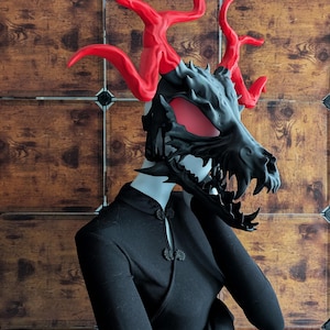 May include: A black and red dragon mask with horns. The mask has a detailed design and a menacing expression.