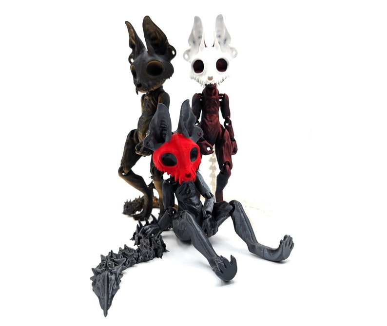 May include: Three articulated skeletal figures with animal-like features. The figures are made of black, white, and red plastic. The figures have a skull-like head with large eyes and a long, thin tail.