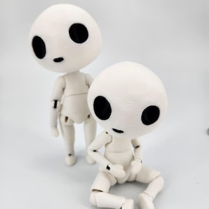 May include: Two white articulated dolls with large black eyes and small black mouths. One doll is standing, the other is sitting with its legs bent. The dolls have a soft, textured appearance and are reminiscent of characters from a fantasy film.