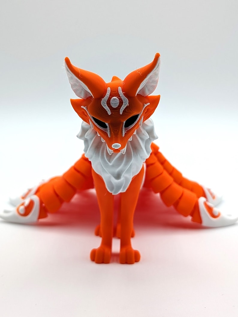 May include: Orange and white 3D printed figurine of a fox with nine tails. The fox has a white mask with a black eye design.