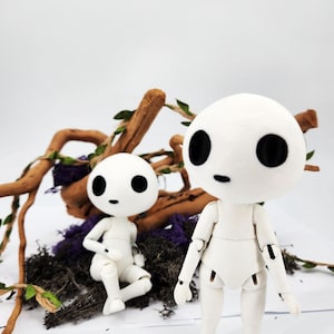 May include: Two white articulated dolls with large black eyes and small black mouths. One doll is standing, the other is seated. They are surrounded by twigs, purple moss, and green leaves against a white background. The dolls have a minimalist design.