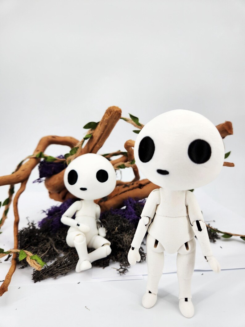 May include: Two white articulated dolls with large black eyes and small black mouths. One doll is standing, the other is seated. They are surrounded by twigs, purple moss, and green leaves against a white background. The dolls have a minimalist design.