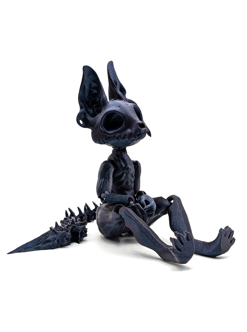 May include: A black skeletal cat figurine with a long, spiky tail. The figurine is made of a dark, textured material and has a detailed skeletal structure.