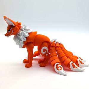 Peut inclure: Figurines de renard articul&eacute; orange et blanc avec plusieurs queues. Le renard a une crini&egrave;re blanche et un visage d&eacute;taill&eacute;. Les queues sont segment&eacute;es et ont des marques blanches.