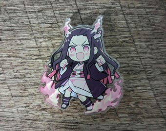May include: A clear acrylic charm featuring a chibi-style anime character with long black hair and pink accents. The character is wearing a kimono and is surrounded by pink flames. The charm is approximately 2 inches tall.