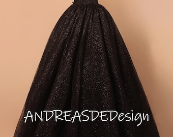 May include: A black formal gown with a V-neckline and spaghetti straps. The dress features a full, sparkling skirt and the text "ANDREASDEDesign" in white.