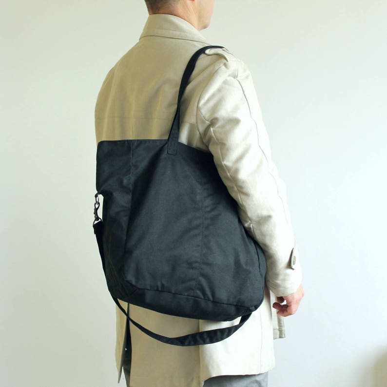 Puede incluir: Un bolso tote negro con una correa para el hombro y una correa cruzada desmontable. El bolso est&aacute; hecho de un material duradero de color oscuro y se lleva al hombro. Un accesorio vers&aacute;til.
