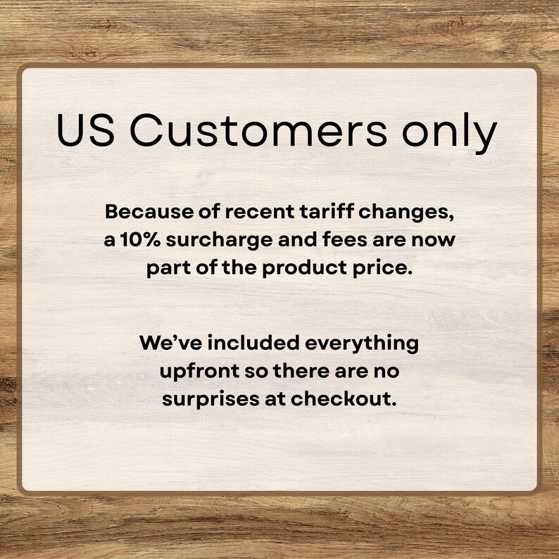 Puede incluir: Un letrero rectangular con borde de madera y fondo beige claro. El texto "US Customers only" est&aacute; en la parte superior. Debajo, el texto explica un recargo del 10% debido a los cambios arancelarios, sin sorpresas al finalizar la compra.
