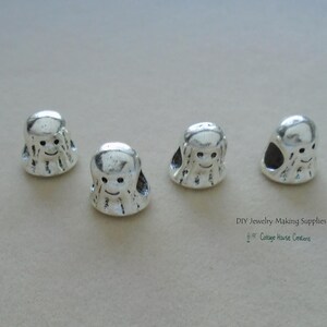 May include: Four silver charm beads in the shape of a cartoon octopus with a smiling face. DIY Jewelry Making Supplies Cottage House Creations.