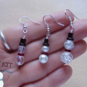 May include: Three pairs of snowman earrings made with beads. The earrings are silver with black, white, and red beads. The snowman earrings are a DIY kit from Cottage House Creations.