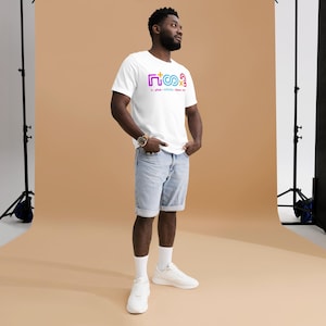 Może przedstawiać: Biały t-shirt z krótkim rękawem z kolorową grafiką na klatce piersiowej z napisem n+infinityx2 oraz frazą n plus infinity times two nowoczesną czcionką, zestawiony z jasnoniebieskimi szortami dżinsowymi, białymi skarpetkami i białymi butami sportowymi.