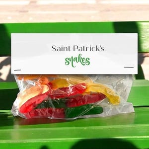 May include: A clear plastic bag filled with red, yellow and green gummy sweets. The bag has a white label that says "Saint Patrick's snakes".