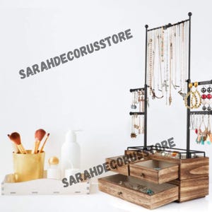 May include: A wooden jewelry organizer with two drawers and a black metal stand with hooks for necklaces and earrings. The stand has a tiered design with multiple levels for hanging jewelry.