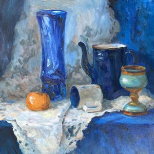 May include: An oil painting still life featuring a tall cobalt blue glass vase, a dark blue ceramic teapot, a small white mug, a light blue and gold chalice, and a single orange fruit resting on a white lace cloth against a deep blue background.