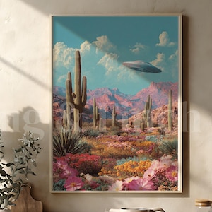 Puede incluir: Una impresión artística enmarcada representa un paisaje desértico con cactus, montañas y un OVNI en el cielo. La obra de arte utiliza colores vibrantes, incluyendo rosa, naranja y azul. La impresión se exhibe en una encimera de cocina.