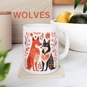 May include: White ceramic mug with a colorful illustration of two wolves with floral designs. The text "WOLVES" is printed in red at the top of the mug.