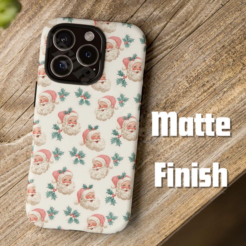 May include: A phone case with a matte finish, featuring a repeating pattern of Santa Claus faces and holly sprigs on a cream background. The case is designed to fit a smartphone, with cutouts for the camera and other features.