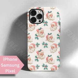 May include: A phone case with a repeating pattern of Santa Claus faces and holly sprigs on a white background. The Santa faces have pink hats and white beards. The text "iPhone Samsung Pixel" is in a pink arrow-shaped box.