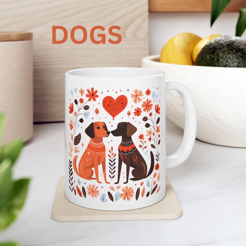May include: White ceramic mug with a colorful illustration of two dogs with a heart above them. The dogs are brown and orange with floral accents. The text "DOGS" is printed above the image.